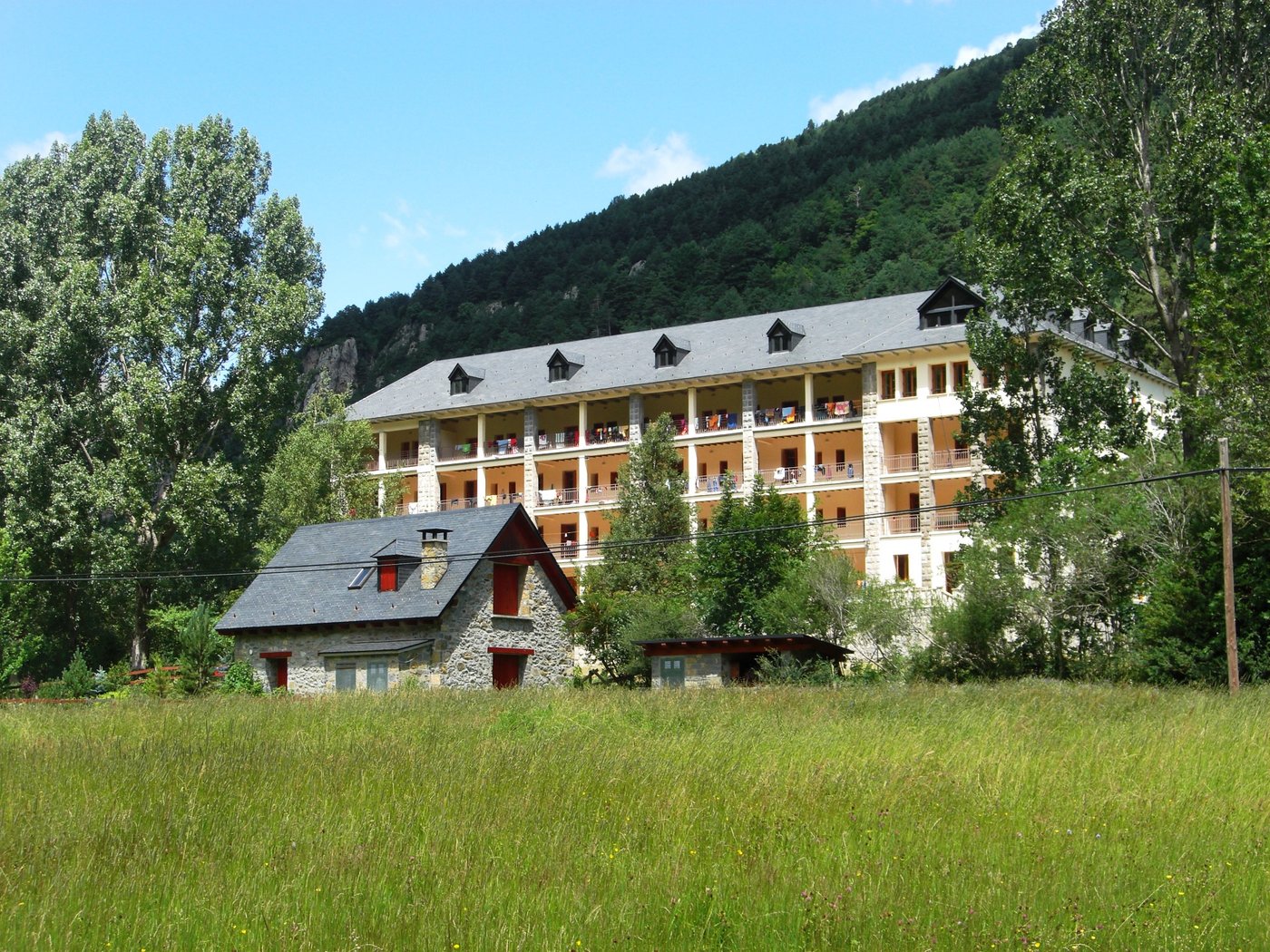 El albergue de Bielsa en el valle, con el bosque y la montaña detrás