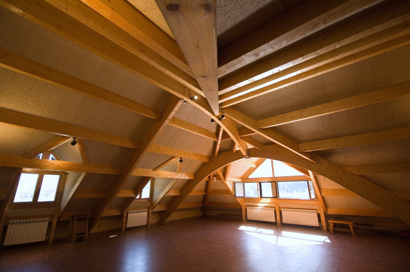 Gran buhardilla de madera con vigas vistas y ventanas al valle