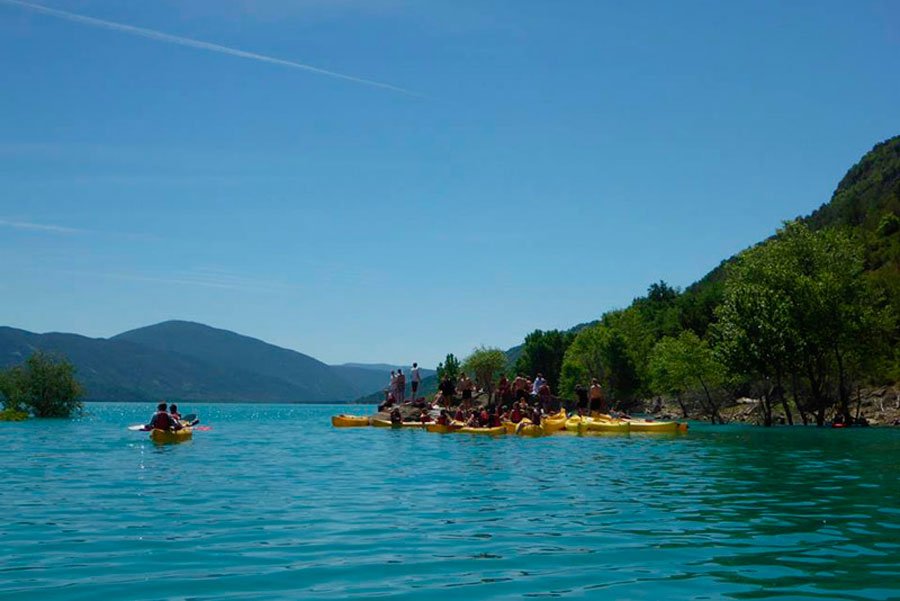 Estudiantes en canoas sobre el agua turquesa del embalse
