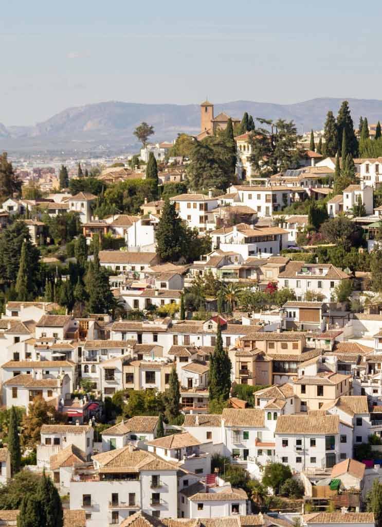 Casas blancas del Albaicín en la ladera, con la vega al fondo