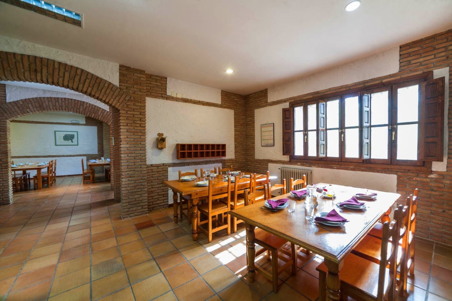 Comedor con mesas de madera y arcos de ladrillo