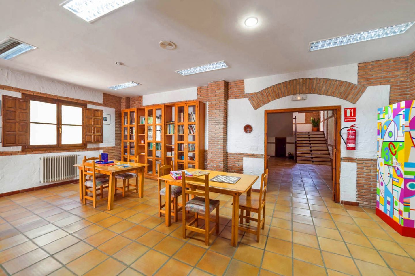 Sala con mesas, juegos de mesa y estanterías de libros