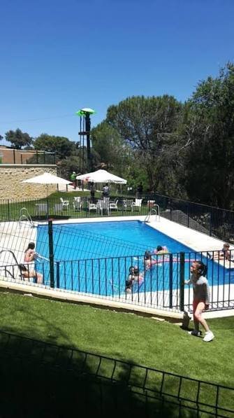 Piscina de la instalación con zona de césped y sombrillas