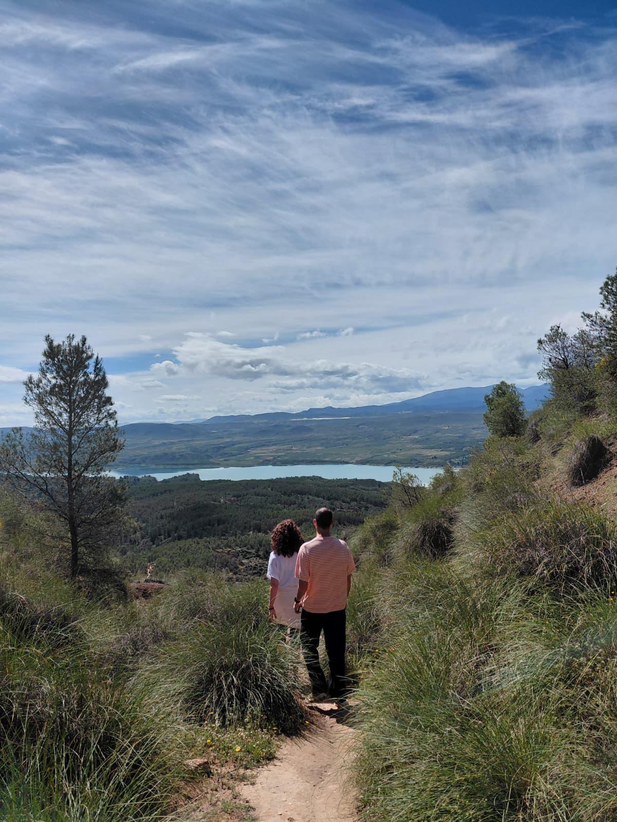 Equipo caminando por un sendero frente al embalse