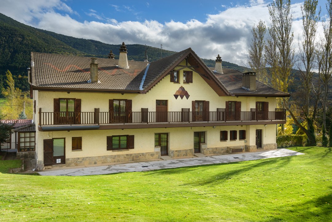 El albergue visto desde la pradera, con la montaña detrás