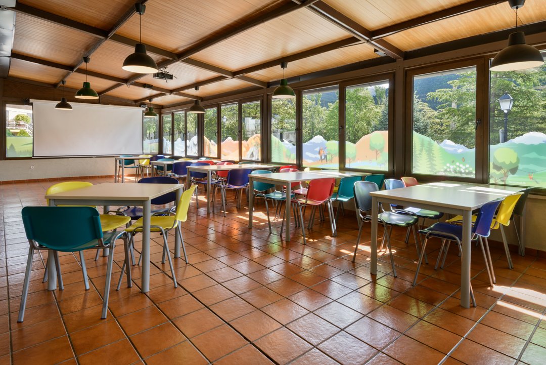 Aula acristalada con mesas de colores y vistas al valle