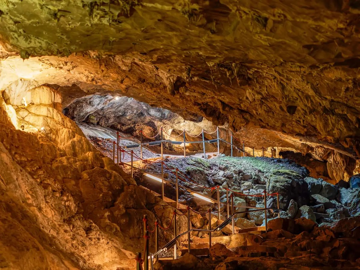Interior iluminado de la Cueva de las Guixas, con pasarelas entre las rocas
