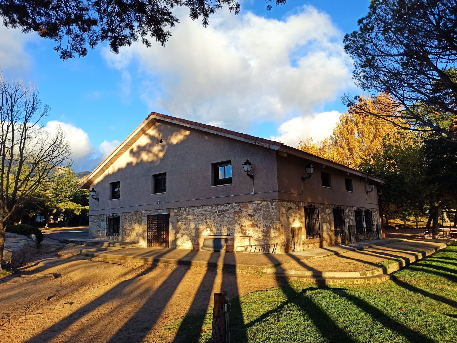 El albergue de la finca de Navacerrada entre árboles, al atardecer