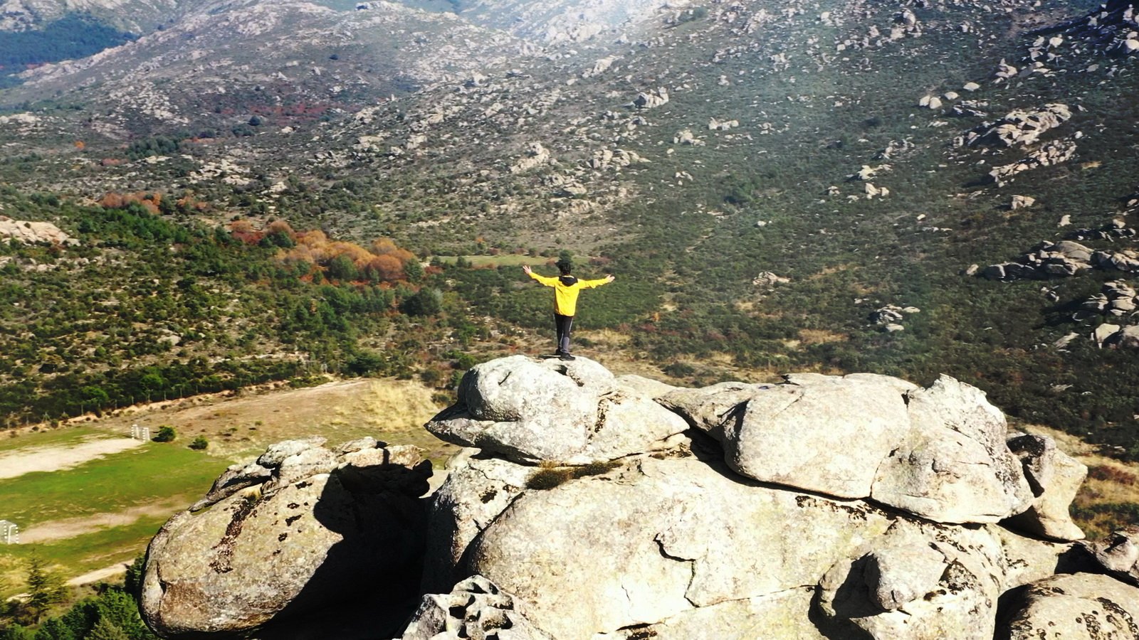 Senderista sobre las rocas de granito con el valle al fondo